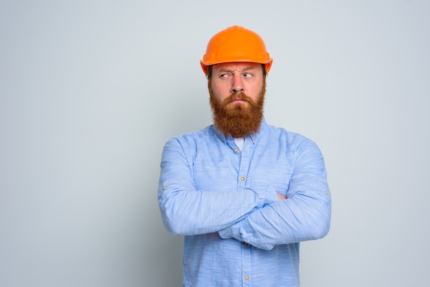 Architecte sceptique isolé avec barbe et casque orange