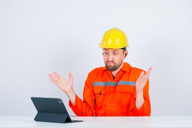 Un architecte surpris regarde sa tablette en ouvrant de larges mains sur fond blanc