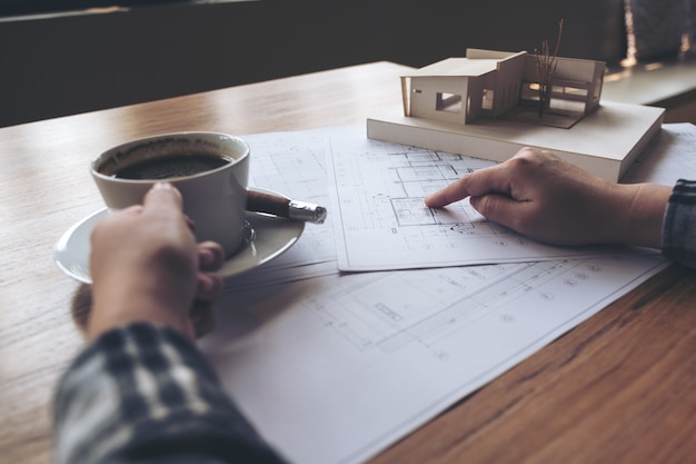 Architecte travaillant sur un modèle d&#39;architecture avec du papier d&#39;atelier tout en buvant du café