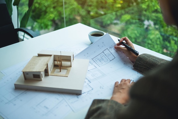 Un architecte travaillant sur un modèle de maison d'architecture avec du papier à dessin d'atelier au bureau