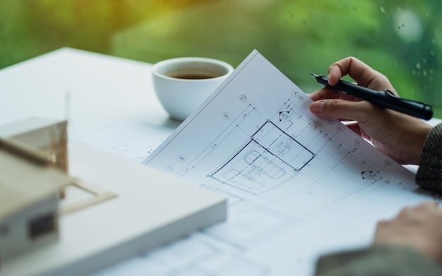 Un architecte travaillant sur un modèle de maison d'architecture avec du papier à dessin d'atelier au bureau