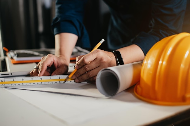 Architectes conceptuels ou ingénieur tenant un stylo pointant des architectes d'équipement sur le bureau avec un plan au bureau