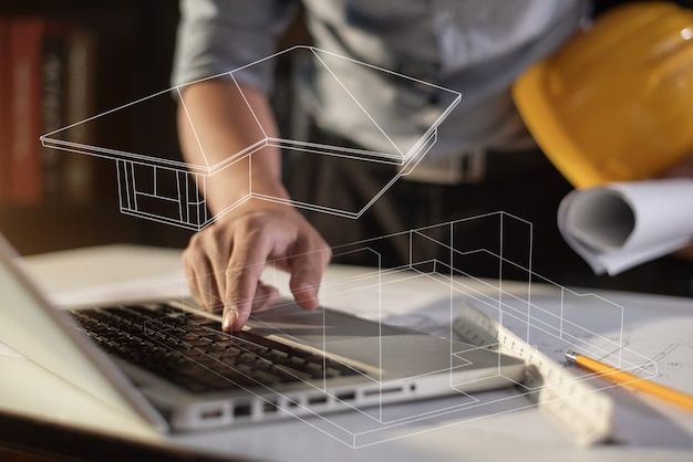 Architectes ou ingénieur tenant un stylo pointant des architectes d'équipement sur un ordinateur portable avec un projet architectural.