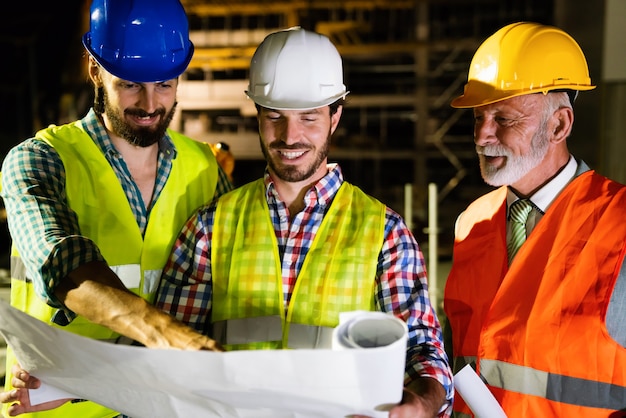 Architectes masculins, ingénieurs analysant le plan sur le chantier de construction