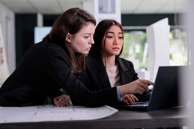 Architectes travaillant avec un logiciel de CAO, discutant de plans architecturaux dans un espace de coworking. Employés du bureau d'architecture au bureau du lieu de travail, projet de construction d'une agence immobilière.