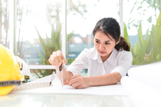 Architecture féminine au bureau utilisant des boussoles pour dessiner un projet d&#39;architectes en papier