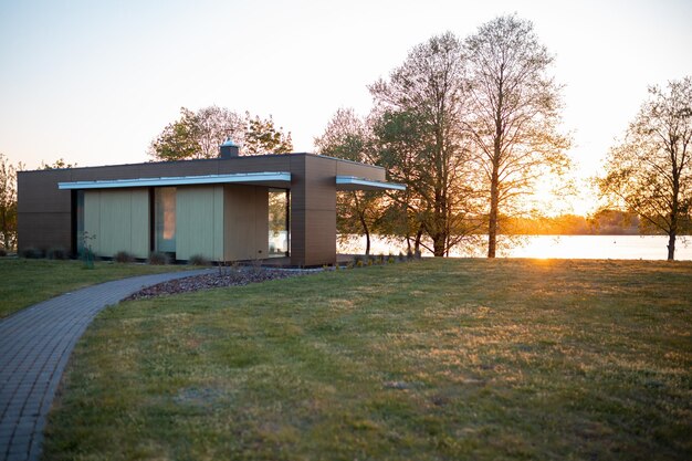 Architecture minimaliste moderne d'une petite maison au bord du lac capturée à l'heure d'or avec un chemin qui y mène