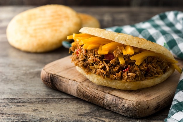 Arepa avec du bœuf râpé et du fromage sur des aliments typiques vénézuéliens en bois