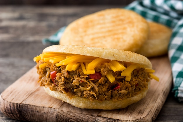 Arepa avec du bœuf râpé et du fromage sur des aliments typiques vénézuéliens en bois