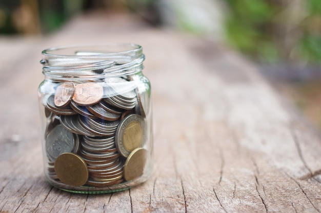 Argent dans le bocal en verre sur table en bois. Concept d&#39;économie d&#39;argent