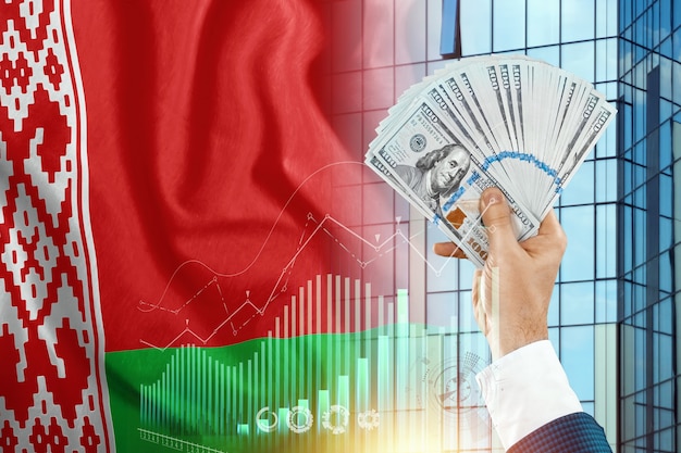 L'argent dans la main d'un homme dans le contexte du drapeau de la Biélorussie.