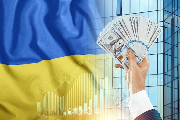 L'argent dans la main d'un homme dans le contexte du drapeau de l'Ukraine