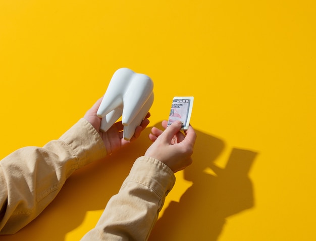 L'argent de la main féminine et la dent sur la surface jaune