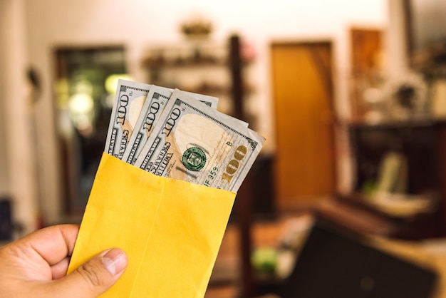 Photo argent - une main tenant une enveloppe avec des billets de 100 $