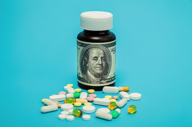 L'argent et les pilules de différentes couleurs sur fond bleu l'augmentation du coût des soins médicaux le