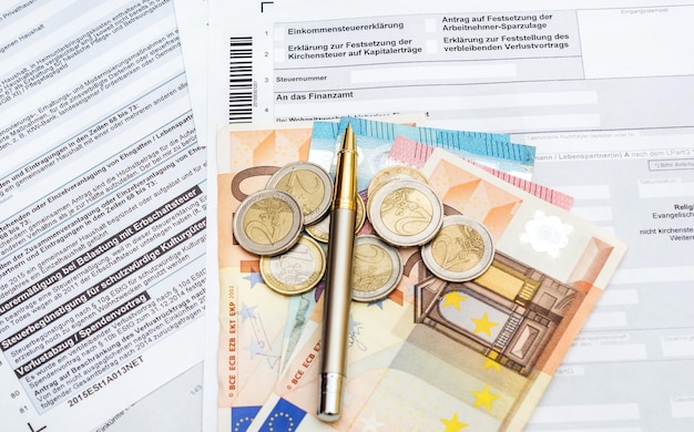 De l'argent et un stylo sur le formulaire d'impôt allemand Vue de dessus TranslationIncome déclaration de déclaration sur la détermination de l'impôt de l'église sur le numéro d'impôt sur les revenus d'investissement au bureau des impôts changement de domicile