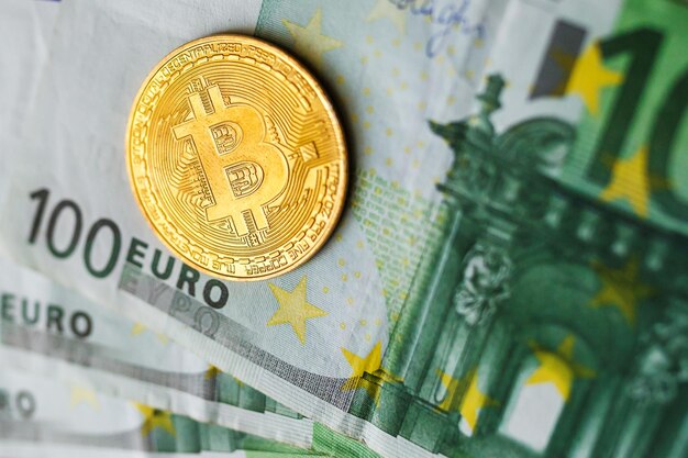 Argent virtuel bitcoin doré sur fond de billets de cent euros Exchange bitcoin cash for euro concept