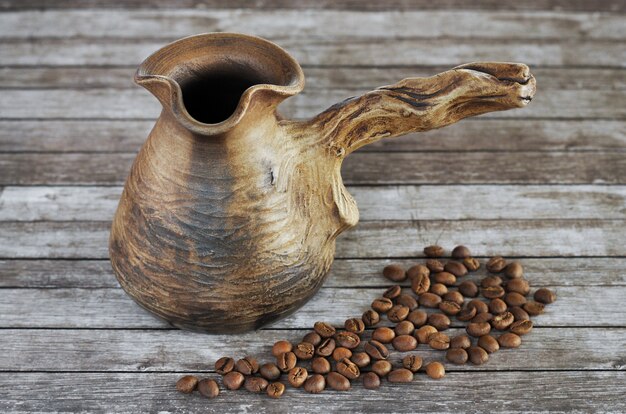 Argile cezve et grains de café sur un fond en bois