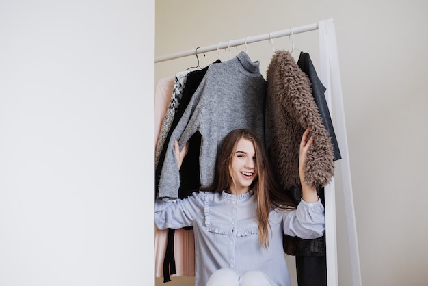 Armoire d'une jeune fille. Robes sur cintres. Choix de farine. Quoi porter? Une fille en pyjama ne sait pas quoi porter.