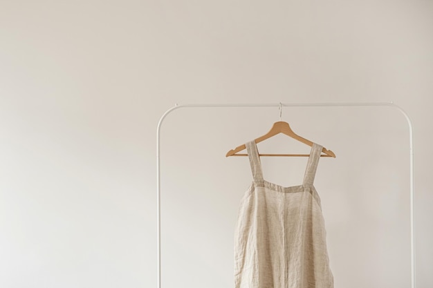 Armoire minimaliste Robe ou robe d'été de couleur beige neutre sur cintre contre un mur blanc Concept de mode esthétique