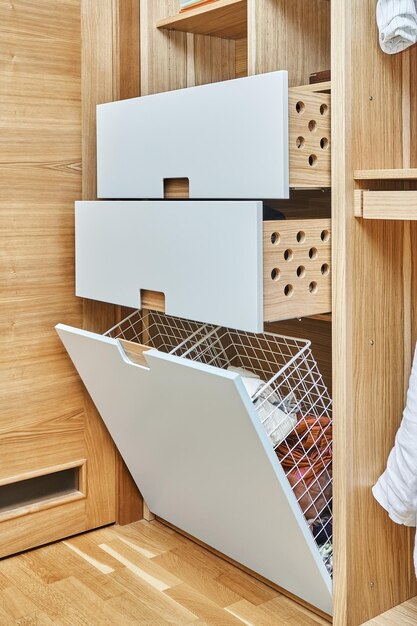 Armoire avec panier à linge ouvert en maille métallique et tiroirs en bois avec portes d'armoire gris clair