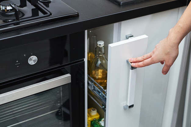 Armoire de rangement de cuisine main femme ouverte dans un intérieur moderne