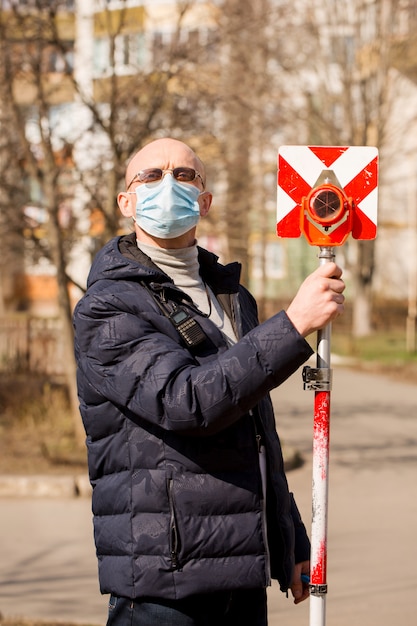 L'arpenteur tient un poteau dans un masque de protection