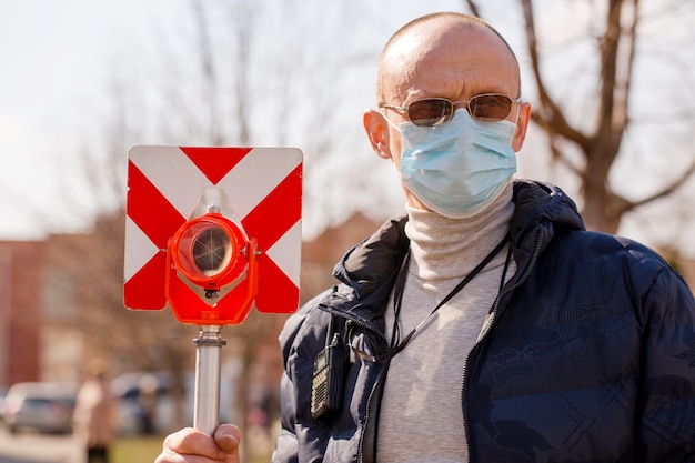 L'arpenteur tient un réflecteur dans un masque de protection