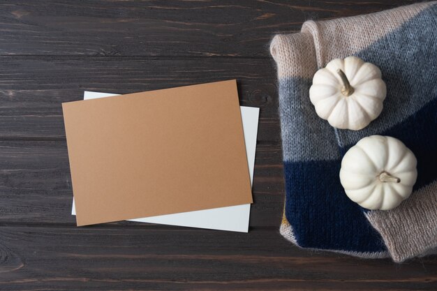 Arrangement d'automne avec citrouille en papier brun vierge et couverture tricotée en laine sur table en bois