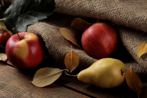 Arrangement d'automne avec des pommes et des poires aux fruits et des feuilles d'automne jaunes sur une table en bois marron