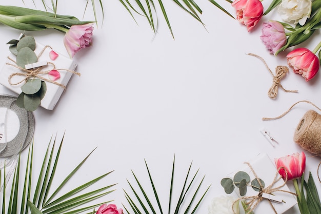 Arrangement festif: boîtes avec des cadeaux, des rubans et des tulipes avec des feuilles de palmier