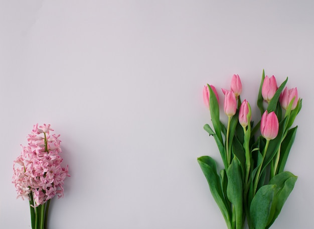 Photo arrangement floral printanier avec tulipes roses et jacinthe rose sur fond clair. notion minimale. espace de copie.