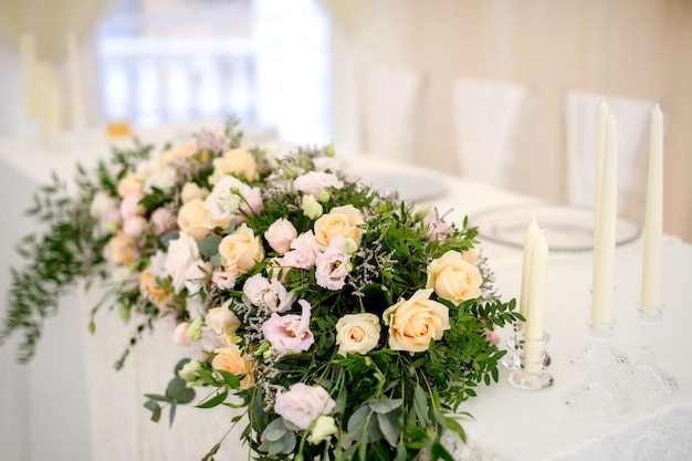 Arrangement floral de roses blanches sur la table du restaurant à côté de bougies