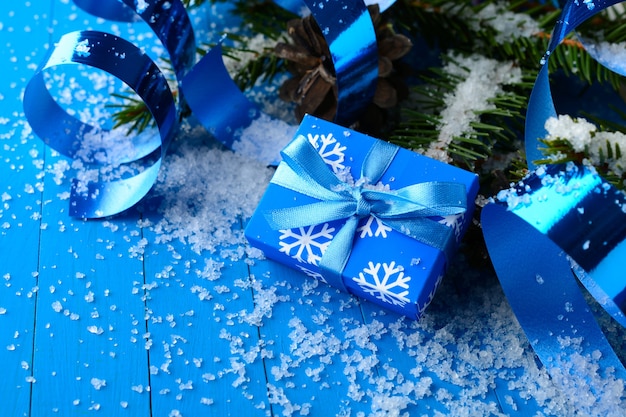 Arrangement magique de coffret bleu avec des rubans et des branches de pin dans la neige.