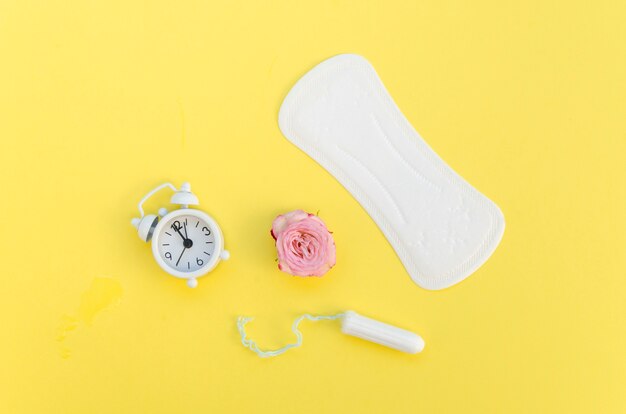 Arrangement de produits d'hygiène féminine avec fleur et horloge