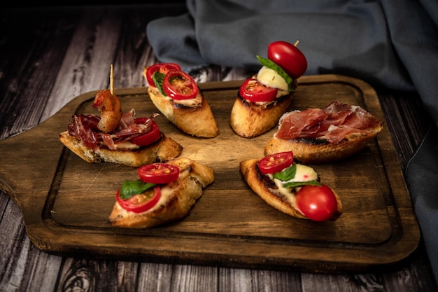 Arrangement d'une sélection de différentes tapas ou bruschettas sur une planche de bois