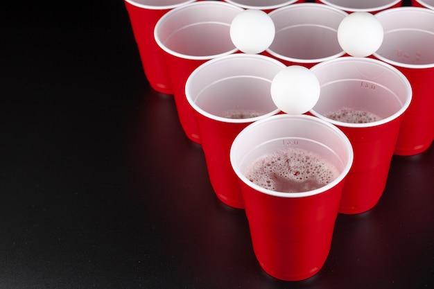 L'arrangement des tasses en plastique rouges pour le jeu de bière pong