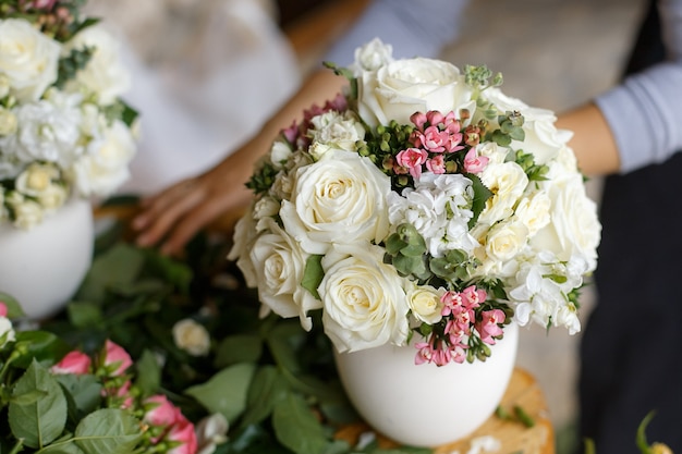 Arrangements de mariage avec un mélange de fleurs fraîches dans des vases blancs.