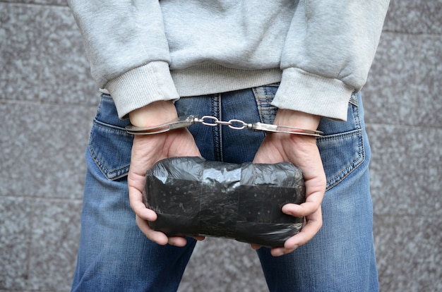 Arrestation d'un trafiquant de drogue menotté par la police avec un gros paquet de drogue à l'héroïne