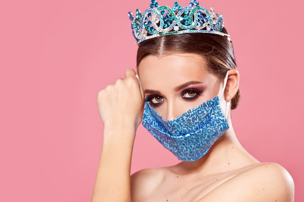 Arrêtez covid-19. Fille dans une couronne et un masque avec des paillettes. Concours de beauté à distance. Mode et beauté. Reine de beauté.