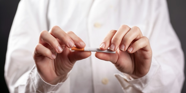 Arrêtez de fumer, une cigarette cassée entre les mains d'un médecin.