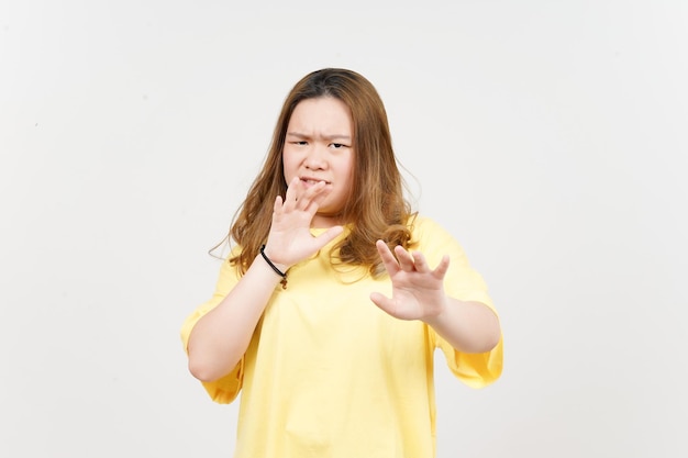 Arrêtez le geste de rejet de la main de la belle femme asiatique portant un t-shirt jaune isolé sur blanc