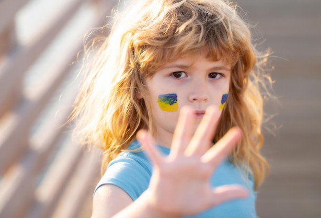 Arrêtez la guerre des gestes de la main drapeau ukrainien sur la joue des enfants jeune enfant lors d'une manifestation avec le drapeau ukrainien k