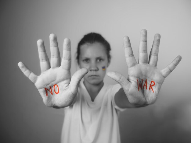 Photo arrêtez la guerre les mains d'un enfant drapeau ukrainien sur les filles joue noir et blanc photo monochrome