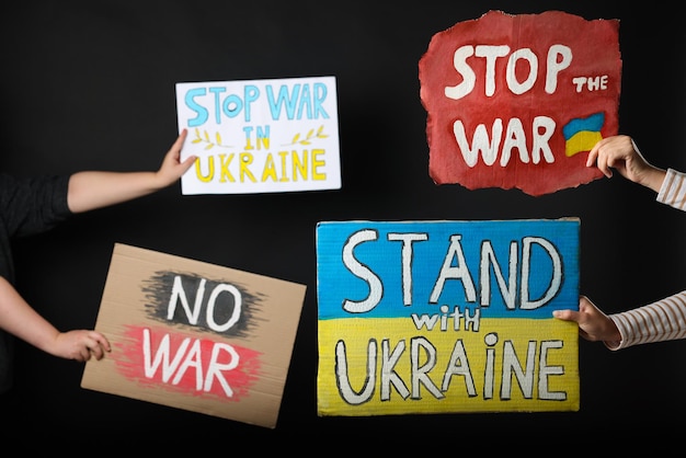 Photo arrêtez la guerre en ukraine personnes tenant des affiches sur fond noir