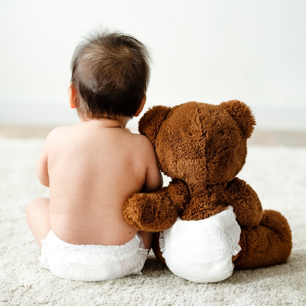 L&#39;arrière d&#39;un bébé avec un ours en peluche