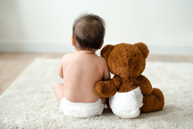 L&#39;arrière d&#39;un bébé avec un ours en peluche