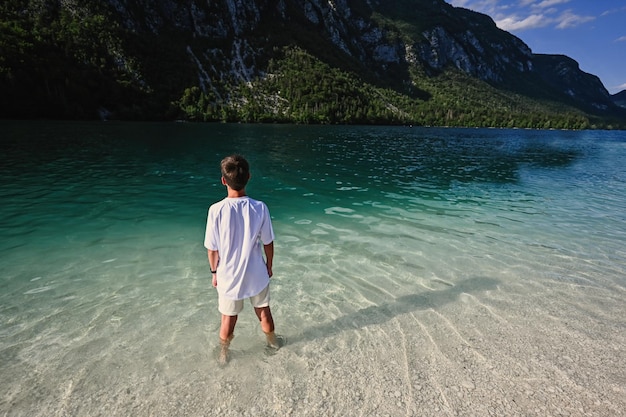 L'arrière du garçon se tient dans le lac de Bohinj, le plus grand lac de Slovénie faisant partie du parc national du Triglav