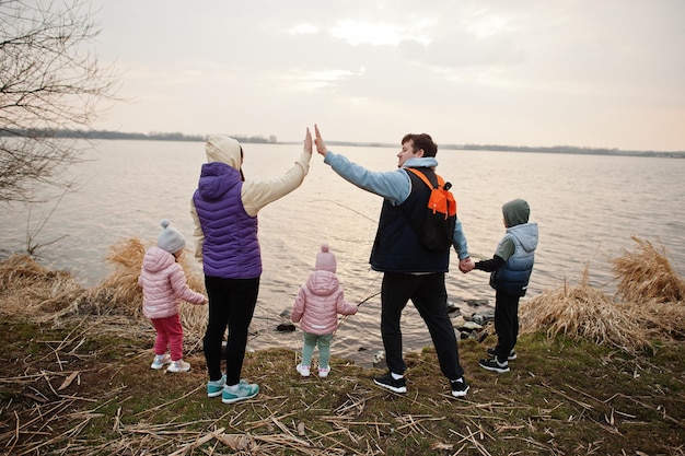 L'arrière d'une famille avec trois enfants au bord du lac Le mari donne à sa femme un high five