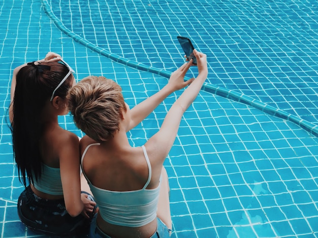 L'arrière de la femme avec un chapeau jaune assis sur la piscine